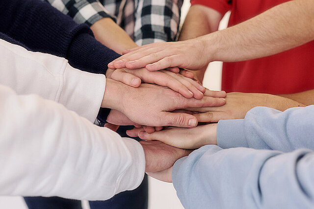 Corporate Volunteering: Mitarbeitende legen Hände übereinander