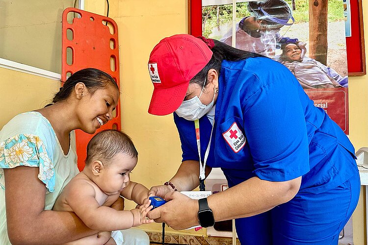 Kolumbien Rotkreuzlerin untersucht Baby auf Schoß der Mutter