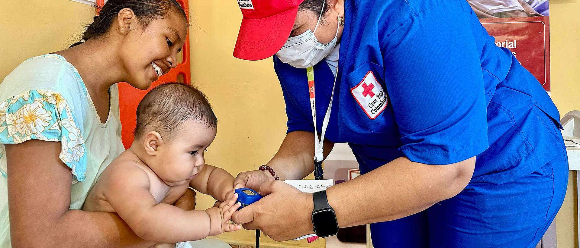 Kolumbien Rotkreuzlerin untersucht Baby auf Schoß der Mutter