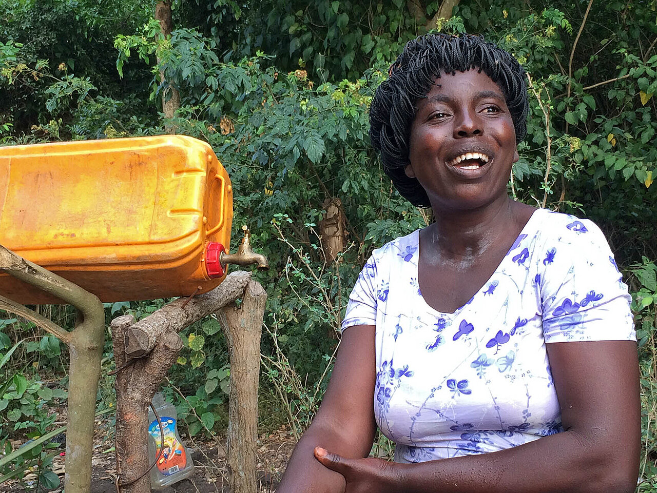 Frau in Togo neben Kanister mit Wasserhahn