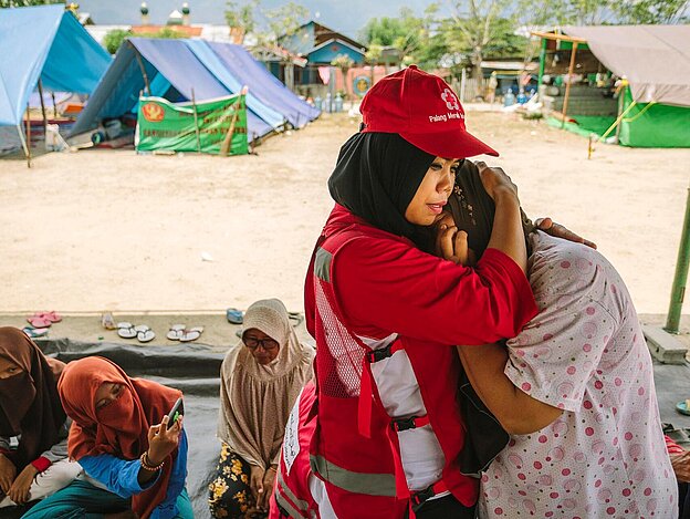 Rotkreuz-Helferin umarmt eine Frau