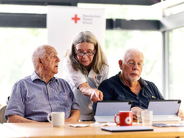 Kurse für Senioren DRKlerin und Senioren schauen auf Tablets