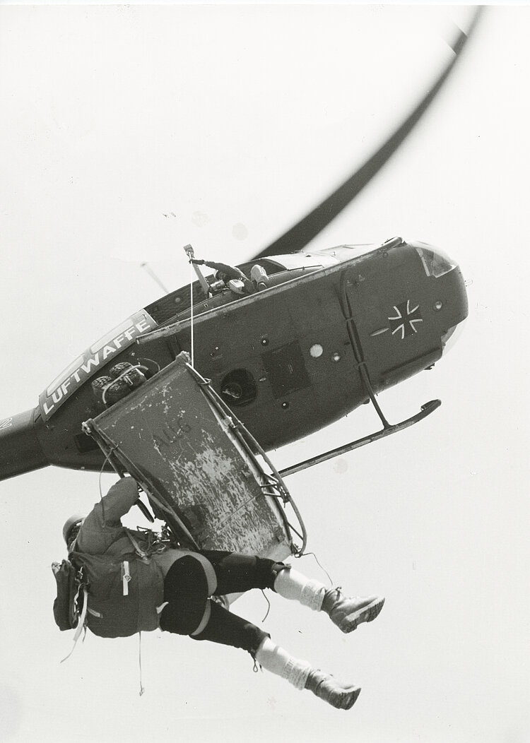 Ein Hubschrauber der Luftwaffe zieht eine Trage (Akja) mit einem Verletzten und dem Bergretter hoch (Archiv Bergecho / DRK)