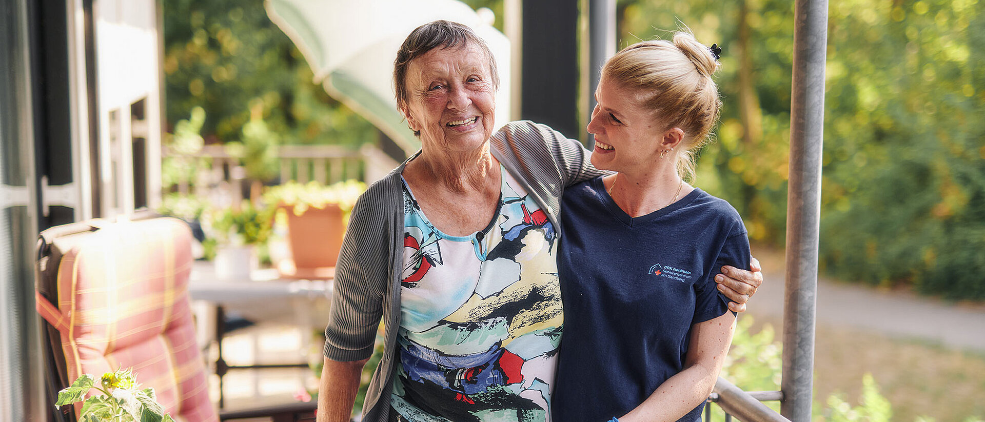 Angebote für Senioren Seniorin lacht mit DRKlerin auf Balkon