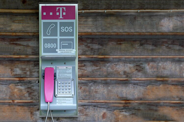Öffentliches Telefon mit Notrufaufschrift an Holzwand