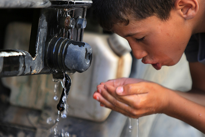 Junge trinkt an Wasserstelle im Irak