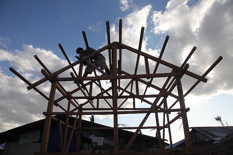 Mann auf dem Dach eines Holzständerwerks