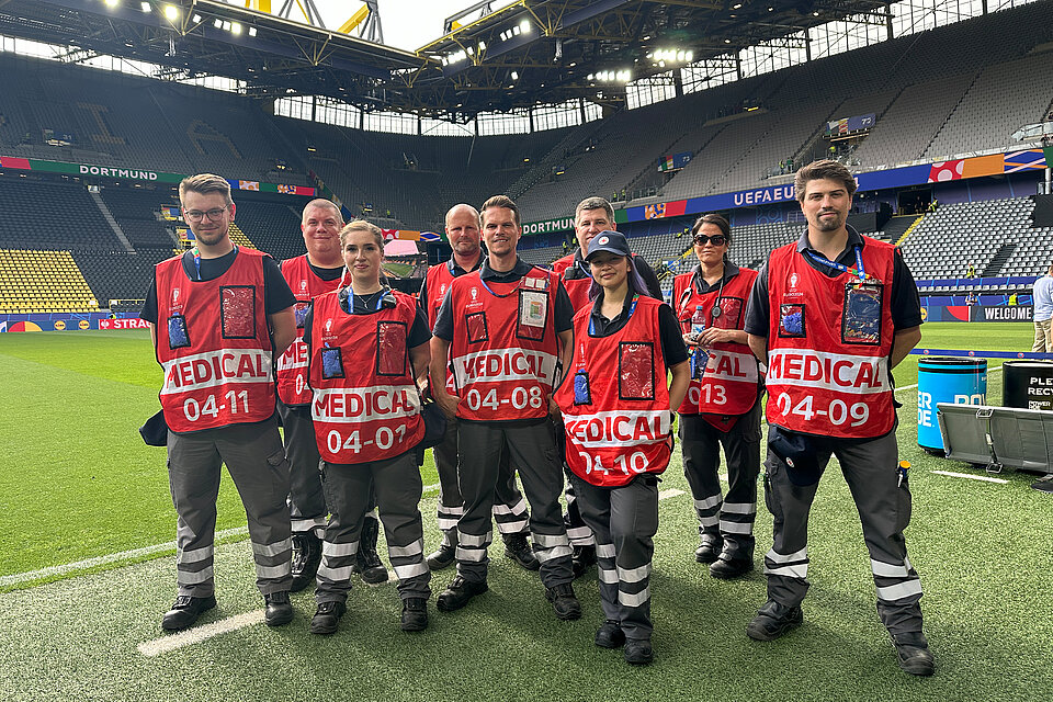 Eine Gruppe von Rettungskräften des Deutschen Roten Kreuzes in roten Westen steht am Spielfeldrand des Westfalenstadions in Dortmund. 
