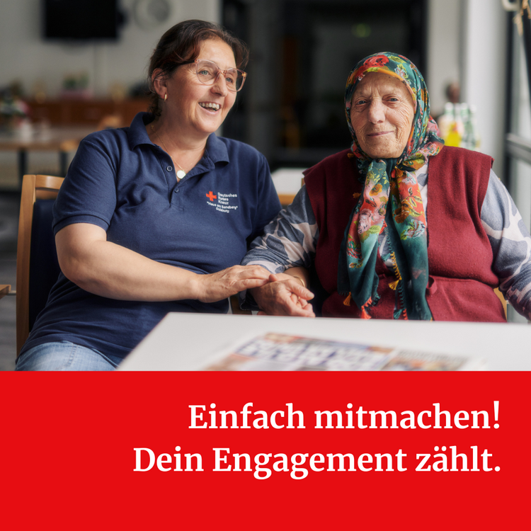 Tag des Ehrenamtes. Einfach mitmachen! Eine Frau mit blauem T-Shirt mit Logo des DRKs sitzt neben einer alten Frau mit buntem Kopftuch und rotem Pollunder. Unter dem Foto steht "Einfach mitmachen! Dein Engagement zählt."