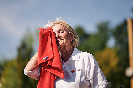 Eine Person wischt sich mit einem Handtuch den Schweiß von der Stirn