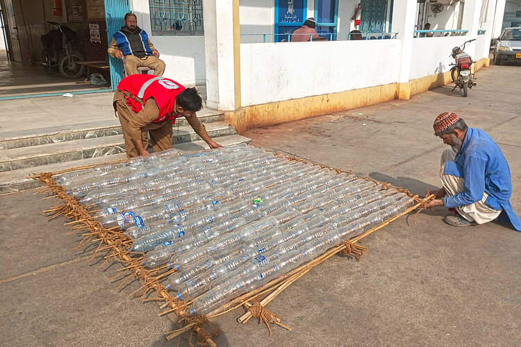 Helfer bauen Dach aus Plastikflaschen