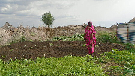 Sudanesin an ihrem Garten mit jungen Pflanzen