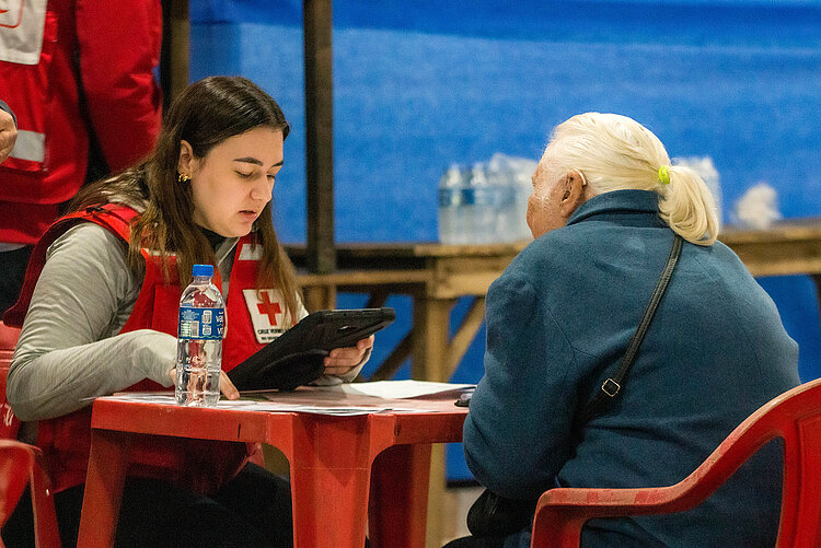 Rotkreuzlerin am Tisch mit Seniorin