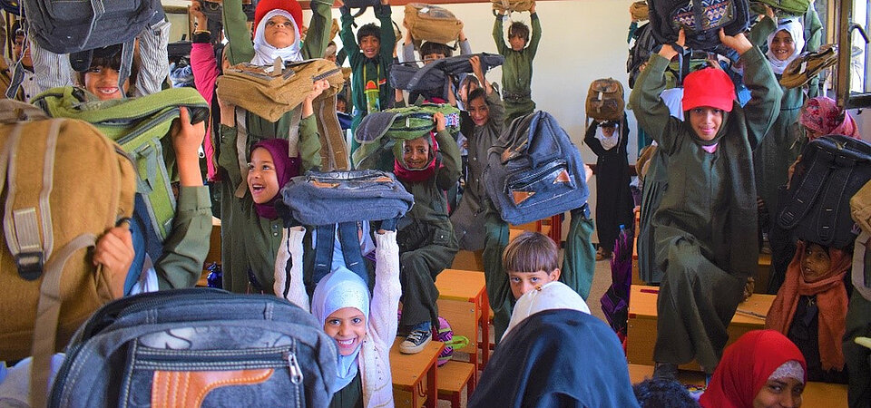 Kinder_im_Jemen_erhalten_Schulranzen Schulkinder halten lachend ihre neuen Schulranzen in die Luft