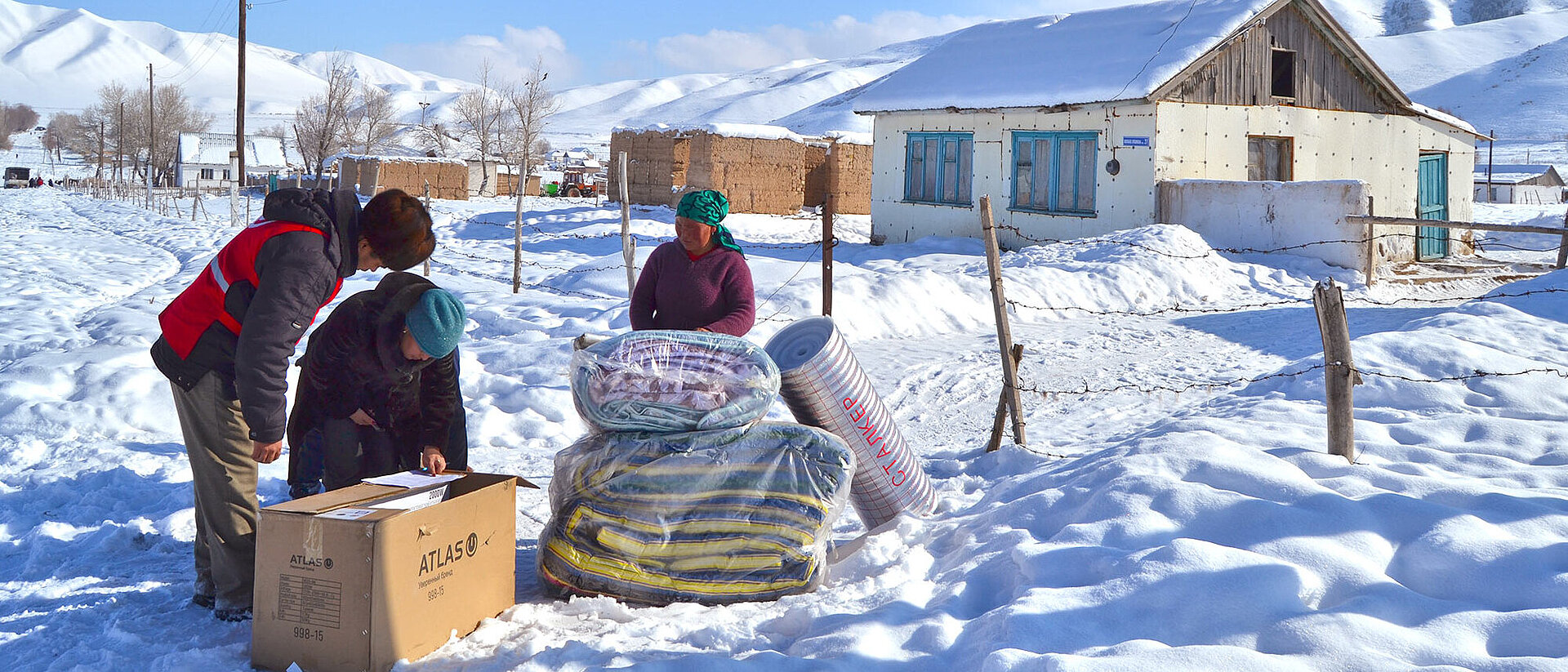 Drei Menschen mit Hilfsgütern im Schnee