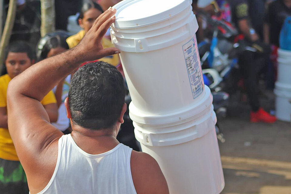 Mann trägt Wasserkanister in Honduras 