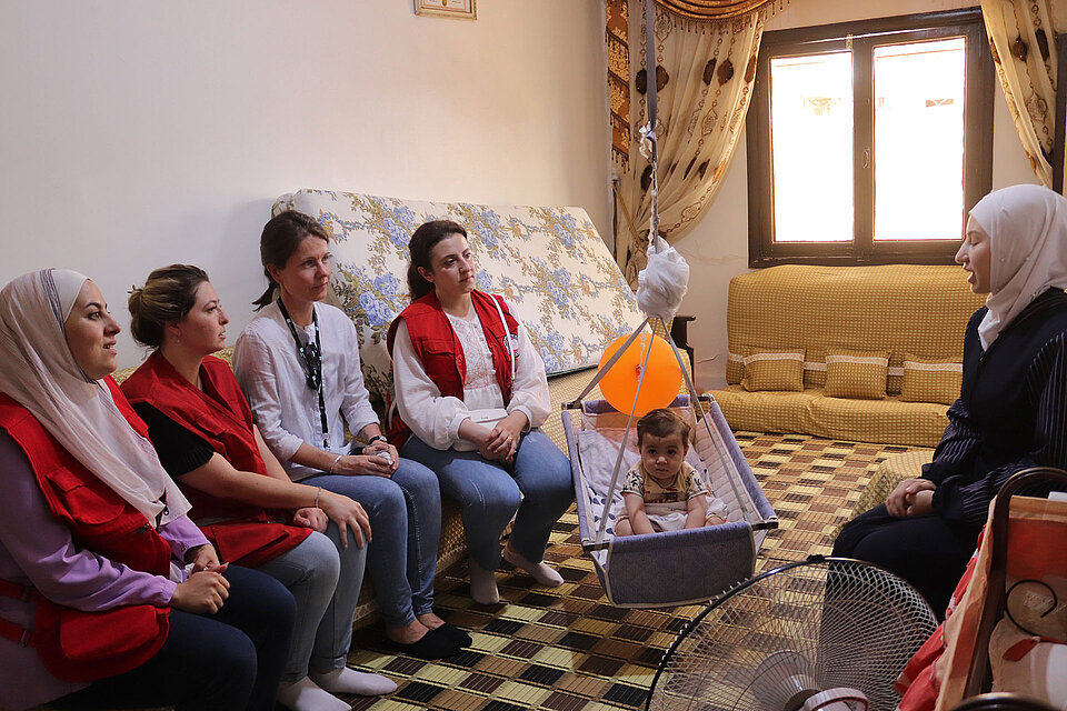 Hier Helferinnen im Gespräch mit syrischer Frau mit Baby  