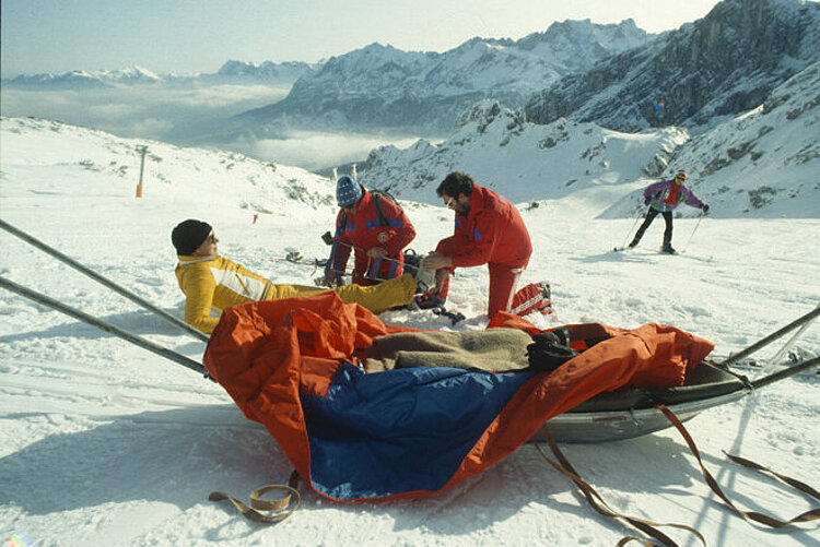 Vorbereitung eines verletzten Skifahrers für den Transport mit einem Akja in den 1990er Jahren (Michel Eram / DRK)