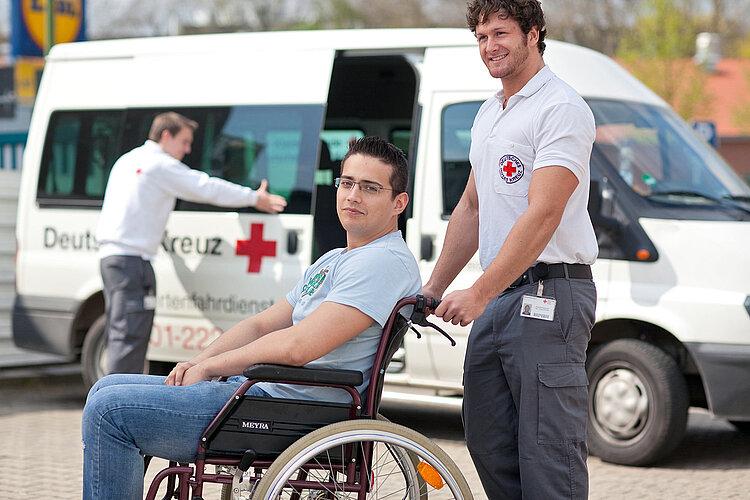 DRK-Fahrdienst Mann im Rollstuhl vor DRK-Fahrdienstwagen