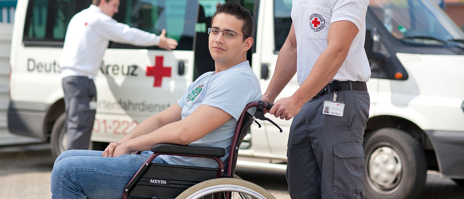 DRK-Fahrdienst Mann im Rollstuhl vor DRK-Fahrdienstwagen