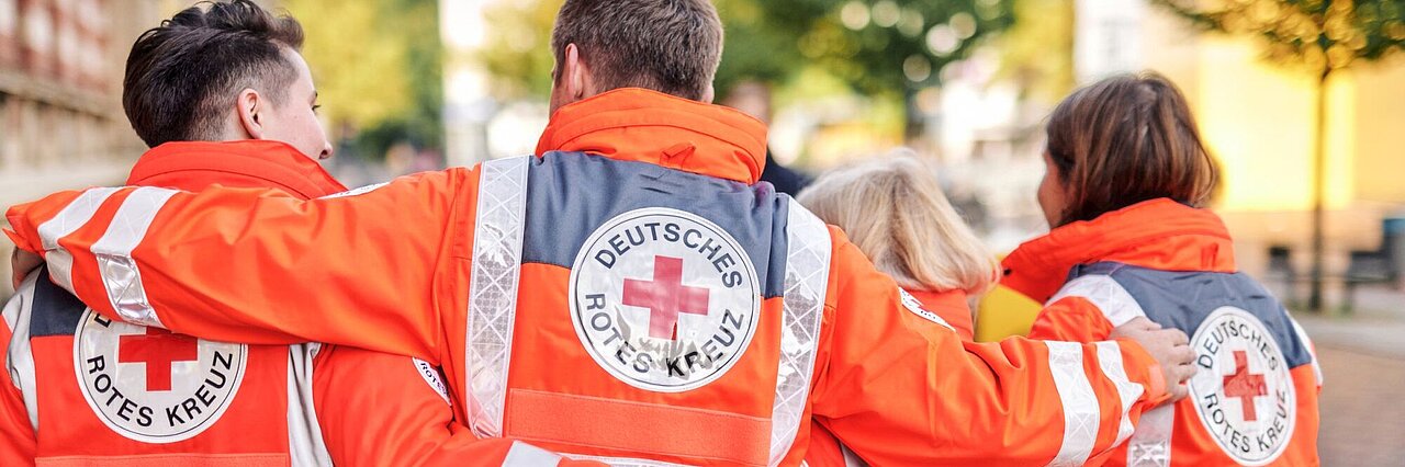 Symbolfoto drei DRK - Einsatzkräfte mit Rettungsdienstjacken mit DRK Symbolfoto drei DRK - Einsatzkräfte mit Rettungsdienstjacken mit DRK - Logo auf dem Rücken - 2021