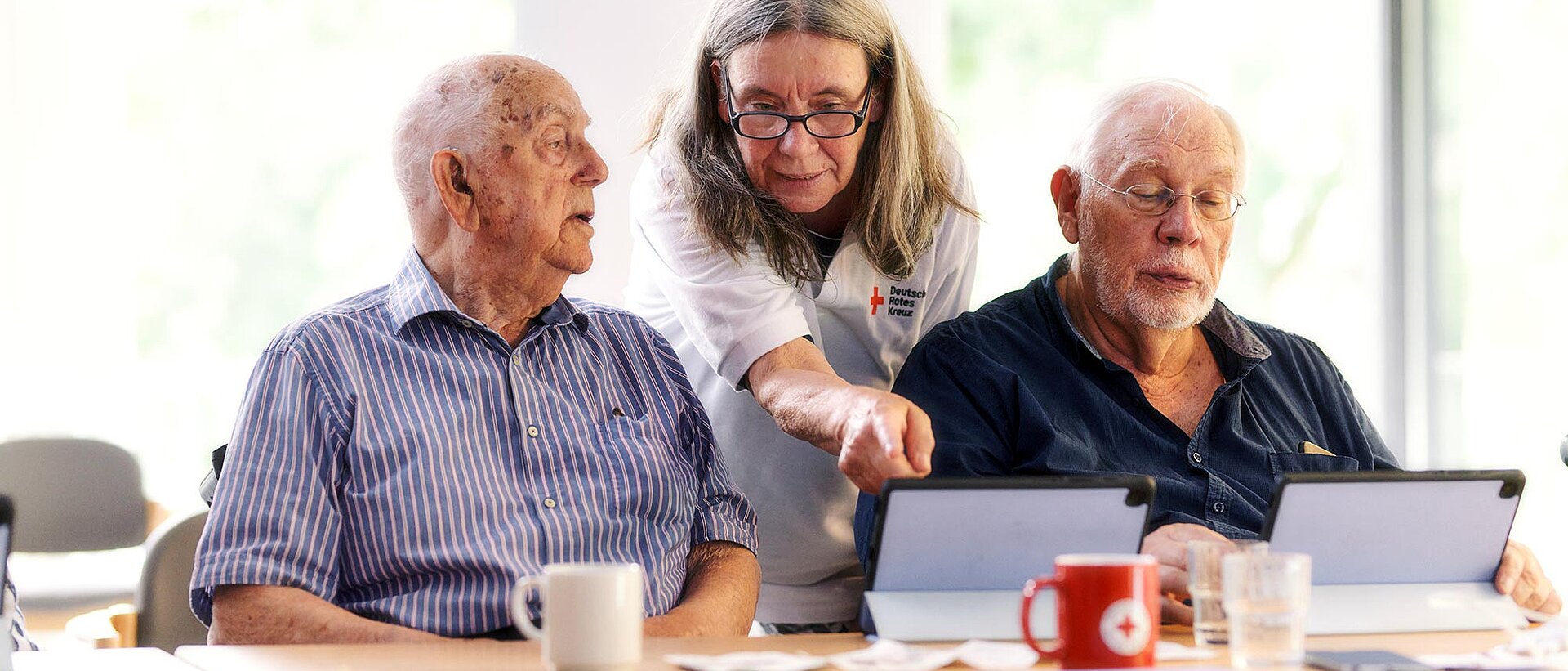 Kurse für Senioren DRKlerin und Senioren schauen auf Tablets