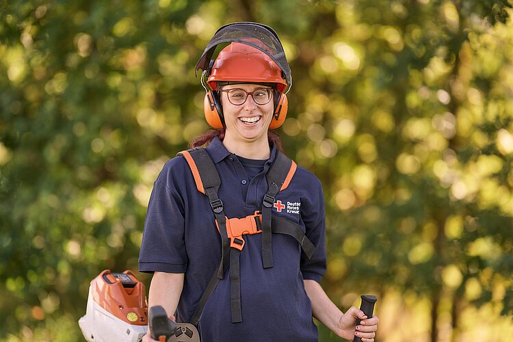 DRK-Werkstätten Junge Frau mit Schutzkleidung und Motorsense