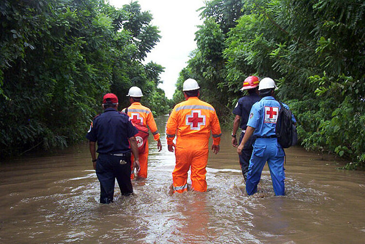 Rotkreuz-Helfer waten in einem Hochwassergebiet