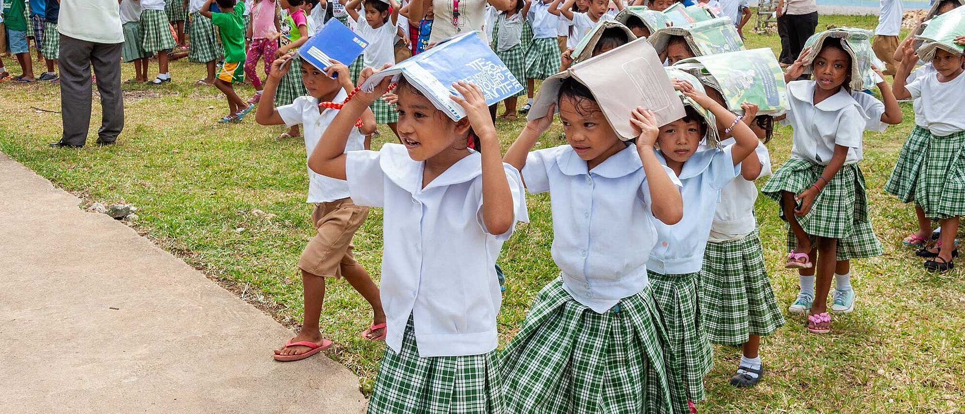 Philippines: Disaster risk reduction Children protecting their heads with books