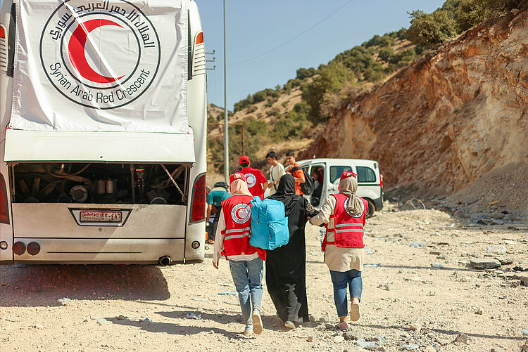 Helferinnen des Syrischen Arabischen Roten Halbmondes mit Geflüchteten 