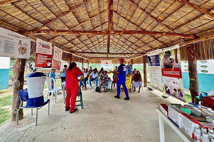 Kolumbien: Gesundheitsaktivitäten Plakate, Rotkreuzler und Begünstigte unter Dach