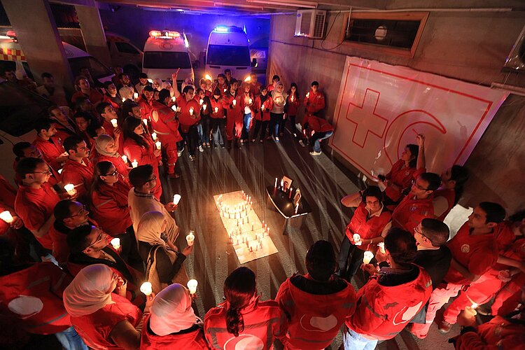 Gedenkfeier für im Bürgerkrieg ums Leben gekommene freiwillige Helfer vom Syrischen Arabischen Roten Halbmond im Zahira Center in Damaskus. Kollegen haben mit Kerzen das Rote Kreuz und den Roten Halbmond geformt.