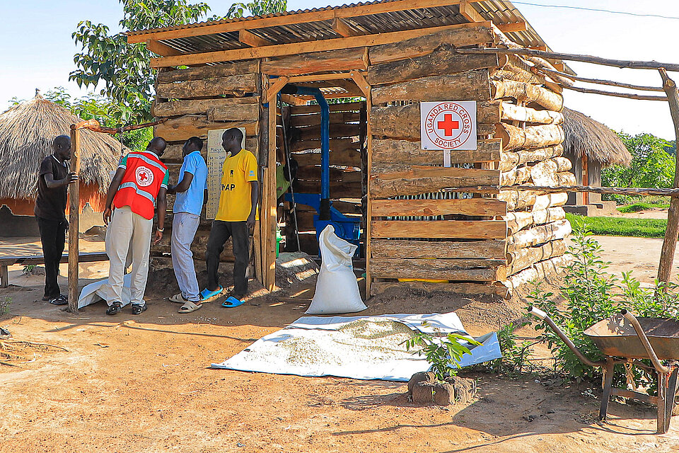 Rotkreuz-Mitarbeitende vor einer Mühle in Uganda 