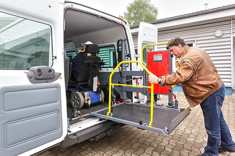 Fahrdienst für Menschen mit Behinderung Mensch im Rollstuhl in Fahrzeug und Fahrer an Rollstuhlrampe