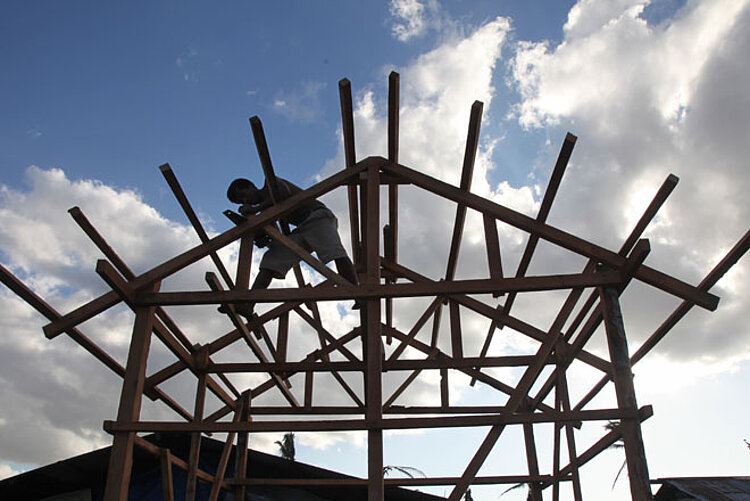 Foto: Handwerker auf dem Holzgerüst eines Daches