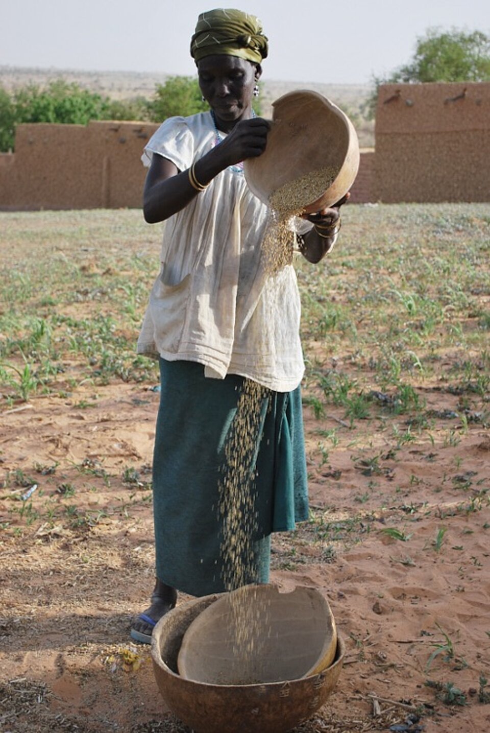 Foto: Eine Frau siebt Zweigen und trockenes Gras.