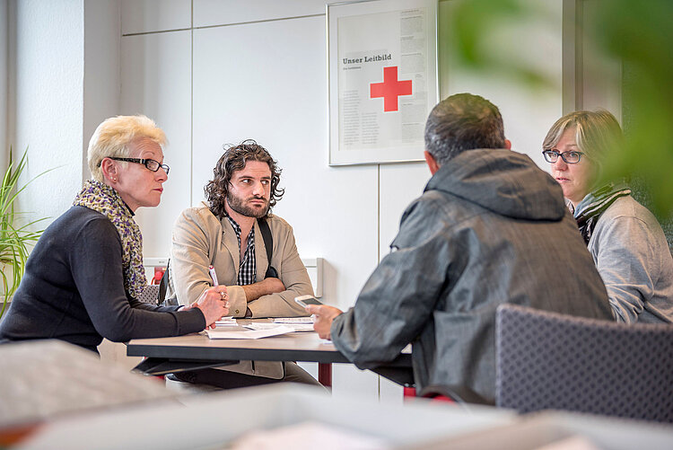 Vier Menschen beim Gespräch am Tisch