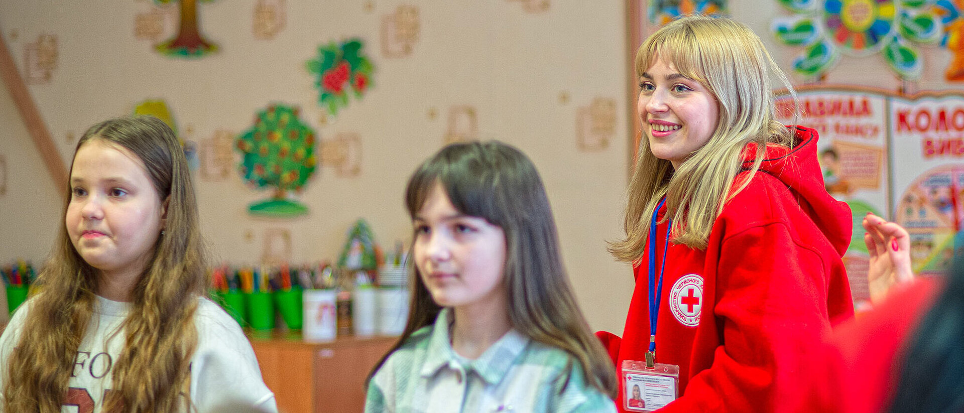 lächelnde Freiwillige steht hinter Kindern
