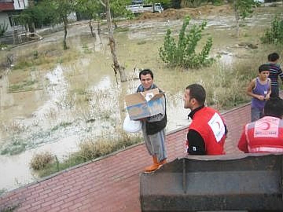 Foto: Ein Helfer des Türkischen Roten Halbmondes bringt Flutopfern Hilfsmittelpakete