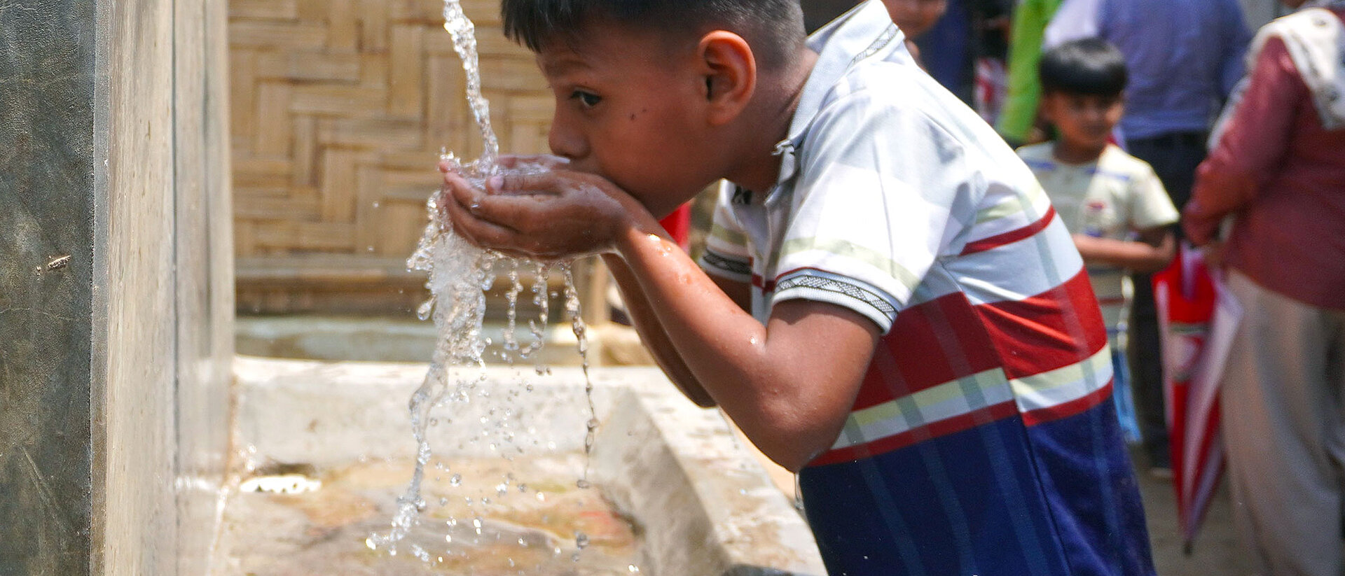 Wasserversorgung Junge trinkt an Wasserstelle