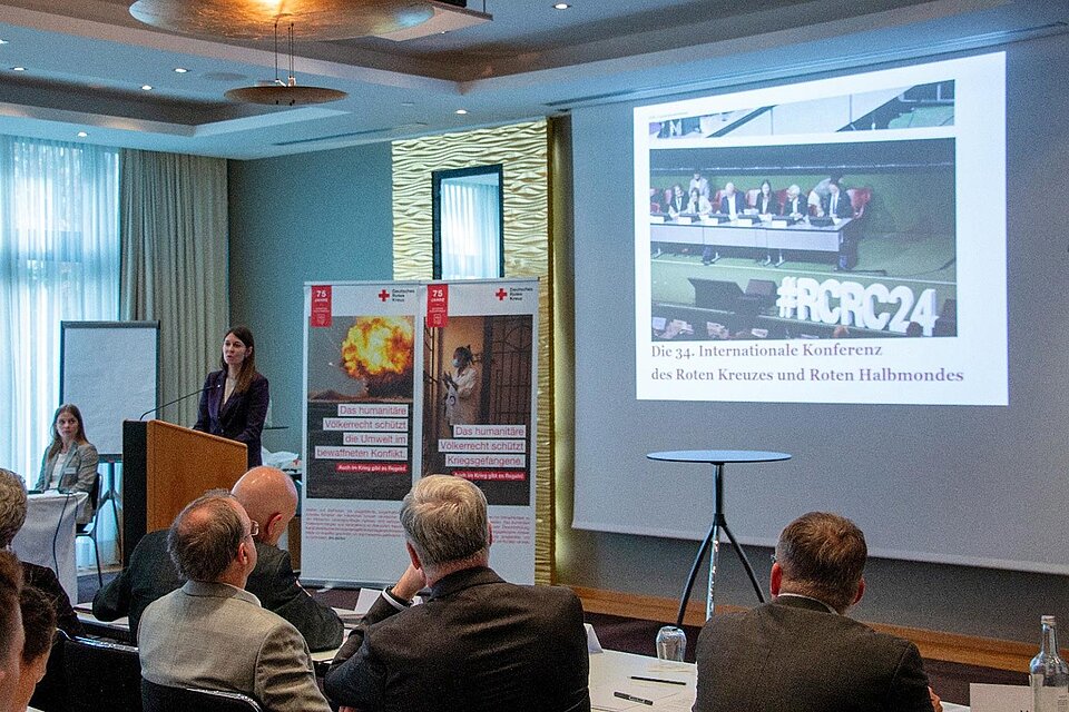 Tagung zum humanitären Völkerrecht Referentin am Pult vor Präsentation