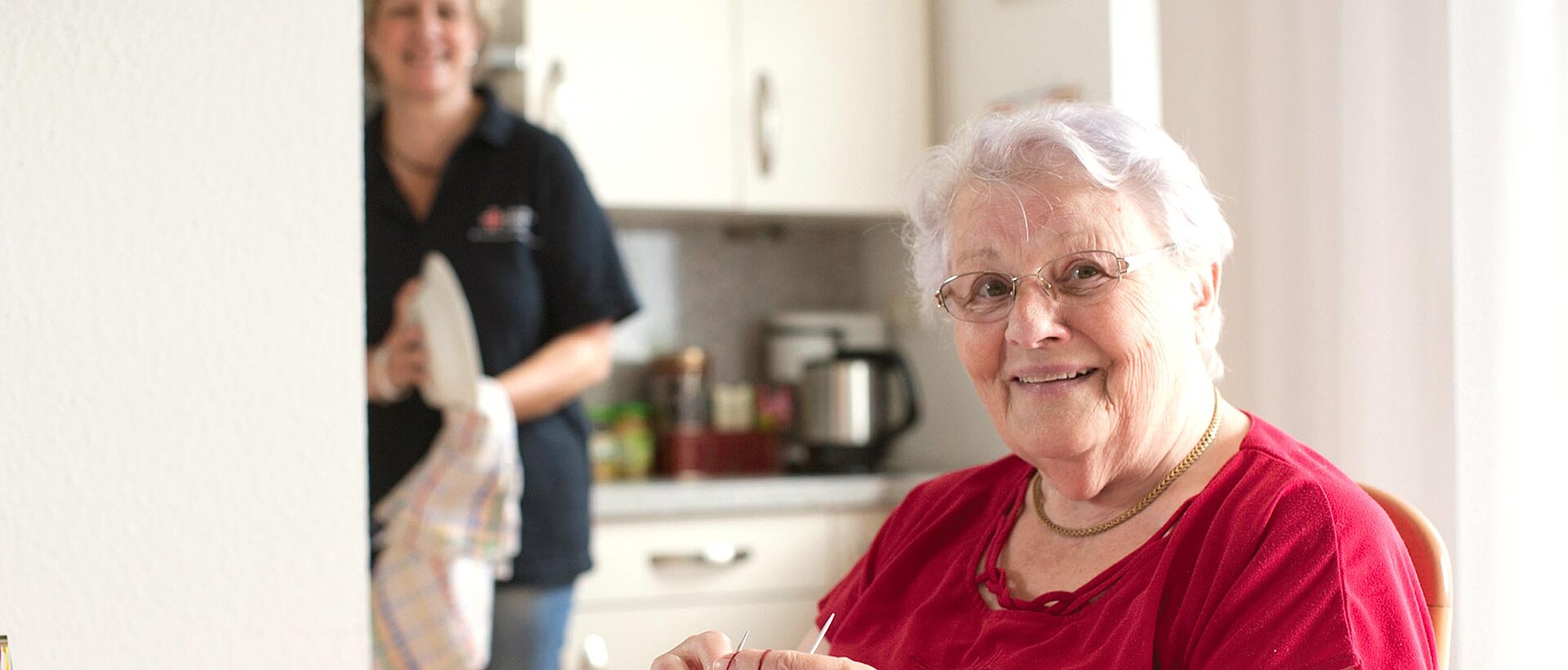 Hauswirtschaftliche Hilfen Pflegerin trocknet Geschirr bei Seniorin